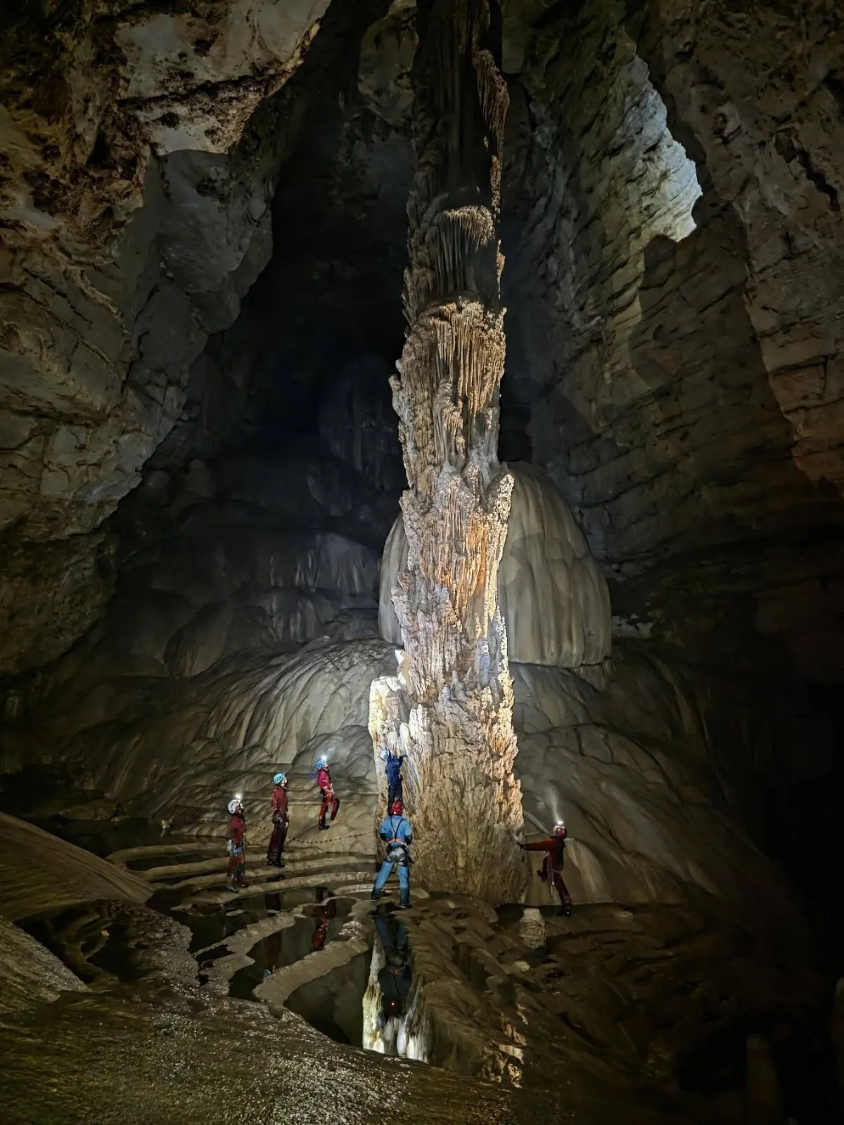 Grupa sa kacigama ispod velikog stalagmita u pećini